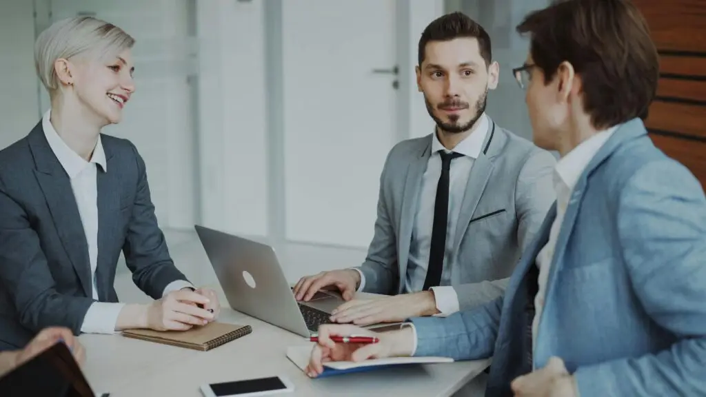 Business professionals in a meeting with laptops and notebooks, discussing strategy.